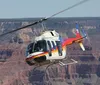 A helicopter is flying in front of the expansive and layered rock formations of the Grand Canyon under a clear blue sky