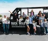 A group of people of various ages posing enthusiastically next to a large open-air tour vehicle labeled BUCK WILD Grand Canyon Hummer Tours