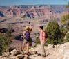 Two hikers are taking a selfie with the expansive view of the Grand Canyon in the background