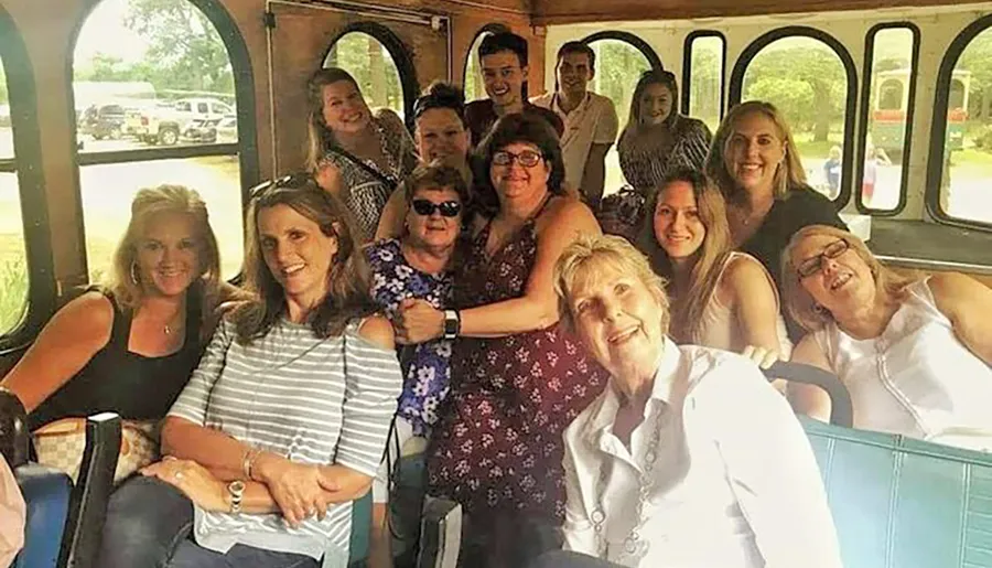 A group of smiling people is posing together inside a bus, radiating a cheerful and friendly atmosphere.