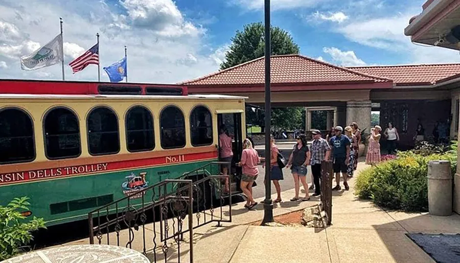 People are boarding a colorful Wisconsin Dells trolley on a sunny day.