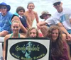 A group of people likely from a wakeboarding camp are posing for a photo with a sign that says Gordy Bubolz Wake Board Camps suggesting a fun day on the water