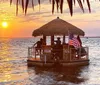 A small boat with a thatched roof bar and an American flag sails on calm waters during a beautiful sunset