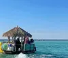 A tiki bar-themed boat carrying people is cruising on clear blue waters