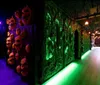 A dimly lit corridor with eerie green lighting features walls decorated with grotesque faces and haunted house-style theming