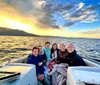 A group of people is enjoying a boat ride on a body of water with a beautiful sunset in the background