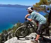 A mountain biker pauses to take in the stunning view of a clear blue lake from a high vantage point