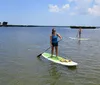 Two women are smiling and standing on paddleboards in the water