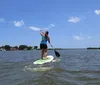 Two women are smiling and standing on paddleboards in the water