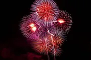 A vibrant display of red and white fireworks blooms against a dark night sky.