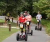 Three people each wearing a helmet are standing outdoors with their individual Segways smiling for the camera