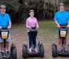 Three people each wearing a helmet are standing outdoors with their individual Segways smiling for the camera