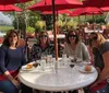 A group of smiling adults is enjoying a meal together at an outdoor restaurant raising glasses in a toast