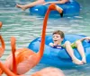 The image shows joyful people riding colorful water slides with the name RipTide Race prominently displayed suggesting an exciting aquatic racing attraction