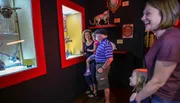 A family is enjoying their visit to a museum, looking at various exhibits with a woman laughing and a child gazing at something with interest.
