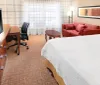 The image shows a neatly-arranged hotel room with two double beds a television and warm lighting