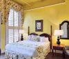 The image shows a well-appointed hotel room with a floral bedspread traditional furniture and a view outside the window