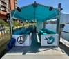 The image shows a turquoise-covered cycle boat docked at a pier adorned with marine-themed decorations ready for a leisurely excursion on the water