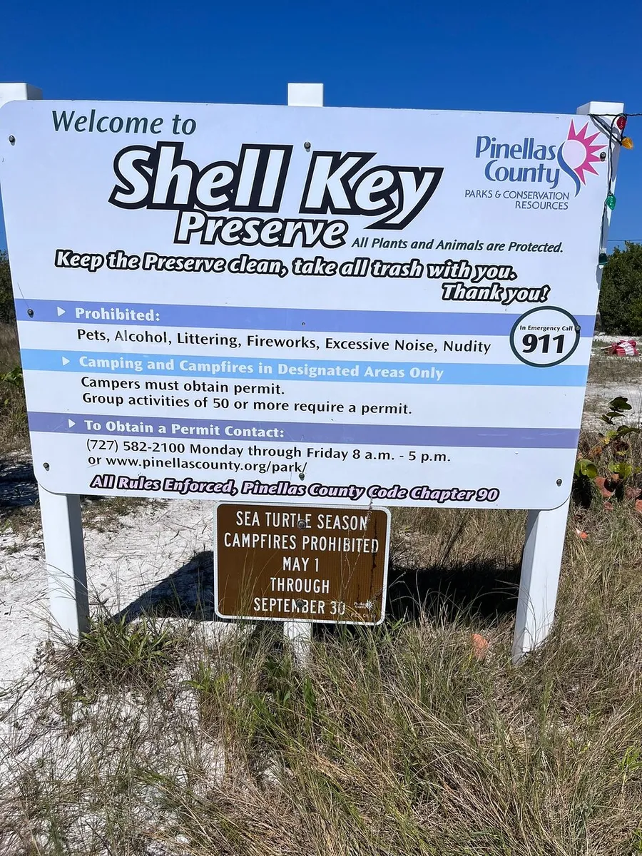 The image shows a welcome sign for Shell Key Preserve in Pinellas County, highlighting preservation rules and contact information, including a note on sea turtle season when campfires are prohibited.