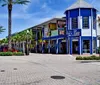The image shows a vibrant street scene with colorful storefronts palm trees and a clear blue sky