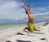 A joyful boy is jumping high on a sunny beach with clear blue skies