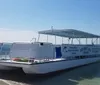 A pontoon boat labeled Adventure Cruises is docked in calm shallow waters under clear skies