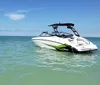 A white and green speedboat is floating on clear blue waters under a sunny sky