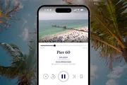 The image shows a smartphone displaying a video of a crowded beach and pier, titled 