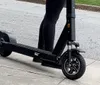 An electric scooters handlebar is equipped with a phone mount holding a smartphone with a green screen