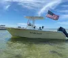 A boat named Thats What Sea Said is anchored in shallow water with the American flag flying from the rear under a clear blue sky