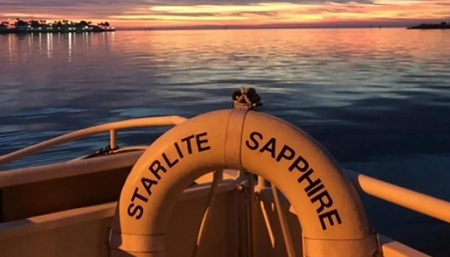 The image shows the back of a boat named STARLITE SAPPHIRE with a breathtaking sunset reflecting off the water's surface in the background.