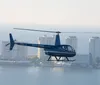 A blue helicopter is flying over a coastal cityscape with high-rise buildings in the background