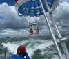 A person on a boat is watching two individuals parasailing over the ocean under a parachute adorned with a red white and blue design