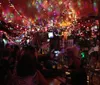 The image shows a bustling bar scene with colorful string lights creating a vibrant cozy atmosphere