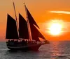 A sailboat is silhouetted against a vibrant sunset over a calm sea