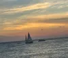 The image shows a sailboat on the ocean at sunset with colorful skies and scattered clouds above