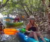 People are kayaking among the mangroves with the person in the foreground smiling for the camera