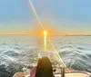 A person enjoys a serene boat ride on a calm sea under a captivating sunset