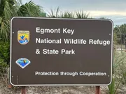 The image shows a sign for Egmont Key National Wildlife Refuge & State Park with the motto 