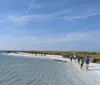 People are enjoying a sunny day on a peaceful beach with clear waters and a blue sky