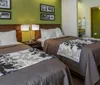 The image shows a neatly arranged hotel room with a king-size bed matching bedside lamps and a green accent wall behind the bed