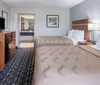 The image displays a neat and tidy hotel room with two double beds featuring simple decor and a window with curtains