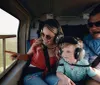 Two adults and a child are wearing headphones while enjoying a scenic helicopter flight