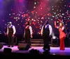 A group of performers are singing on stage under colorful stage lighting