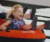 A young girl is joyfully sliding down in an orange Tube Pro water slide tube