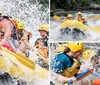 A group of people wearing life jackets and helmets are joyfully white water rafting splashing through a rapid