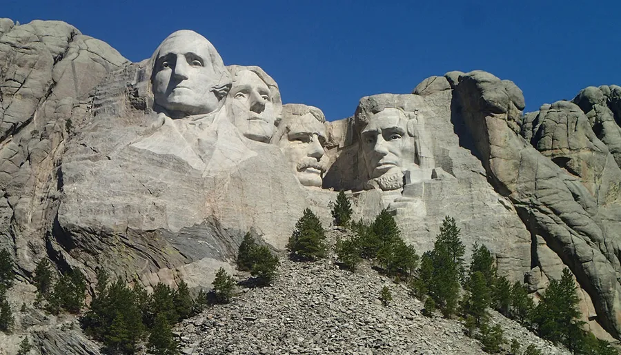 The image shows a clear view of the Mount Rushmore National Memorial, with the carved faces of four U.S. presidents on a sunny day.
