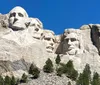 The image shows the iconic Mount Rushmore National Memorial featuring the carved granite faces of four former US presidents