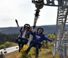 Two people are enjoying a ride on a zipline with a sign for All You Can Eat Pancakes visible in the background