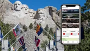 The image shows the iconic Mount Rushmore National Memorial with the heads of four US presidents carved into the granite, alongside a mobile phone displaying a tour app interface, suggesting a modern way to explore this historic site.